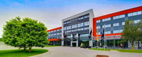 a large building with a tree in front of it at Novina Hotel Herzogenaurach Herzo-Base in Herzogenaurach