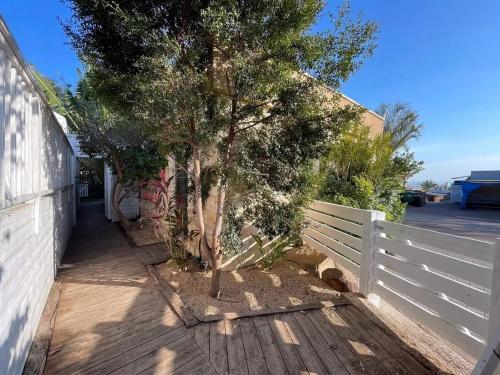 a white fence next to a tree next to a building at סוויטות טיפאני של רשת לב הגולן - 3 סוויטות מדהימות עם בריכה פרטית in Had Nes
