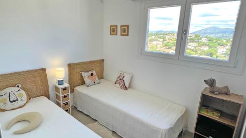 deux lits dans une chambre avec deux fenêtres dans l'établissement Coteaux du Préconil, à Sainte-Maxime