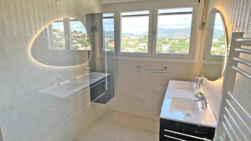 une salle de bain avec deux lavabos et deux miroirs et fenêtres dans l'établissement Coteaux du Préconil, à Sainte-Maxime