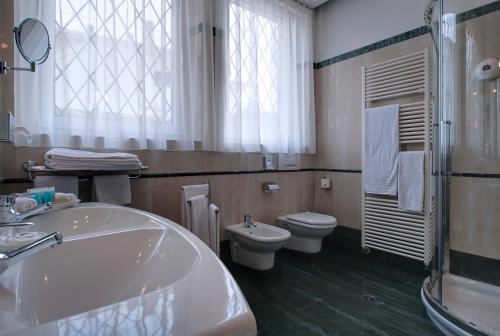 a bathroom with a tub and a toilet and a sink at Palace Hotel San Pietro in Bardolino