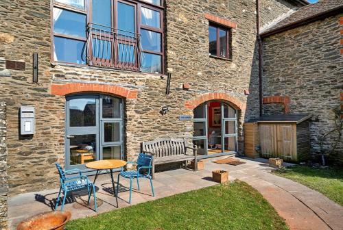 a patio with chairs and a bench in front of a building at Finest Retreats -Little Granary in Salcombe
