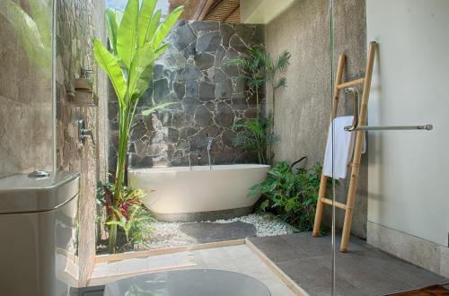 a bathroom with a bath tub with plants in it at Anusara Luxury Villas in Ubud
