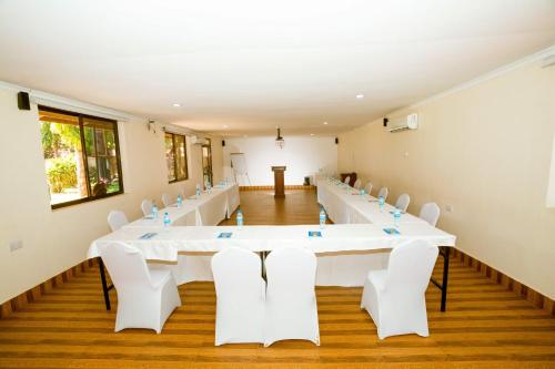 a large room with a long table and white chairs at Keys Hotel in Moshi
