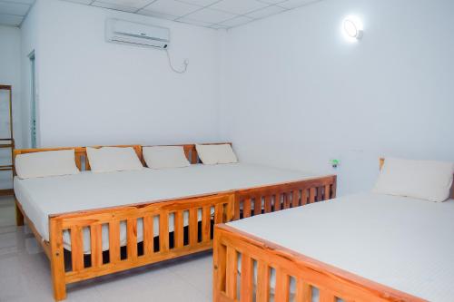 two beds in a room with white sheets at Hotel Sanjana & Restaurant in Polonnaruwa