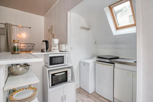 - une petite cuisine avec des armoires et des appareils blancs dans l'établissement Le Nid - Place Imbach, à Angers