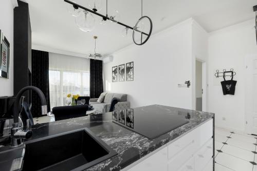 a kitchen with a sink and a living room at Luxury Apartment 23 basen i sauna D&D Apartments in Dziwnów