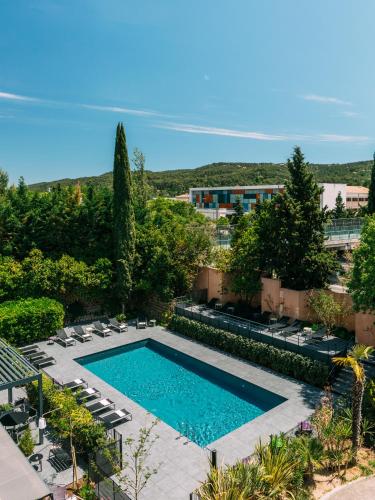 une piscine avec des chaises longues et un complexe hôtelier dans l'établissement Escale Oceania Aix-en-Provence, à Aix-en-Provence