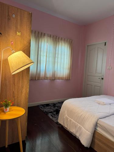 a bedroom with a bed and a table and a window at ริมน้ำบ้านแม่ อัมพวา เหมาหลัง 5 นอน พักได้ 10 คน in Samut Songkhram