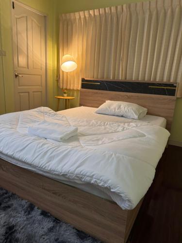 a bed with white sheets and pillows in a bedroom at ริมน้ำบ้านแม่ อัมพวา เหมาหลัง 5 นอน พักได้ 10 คน in Samut Songkhram