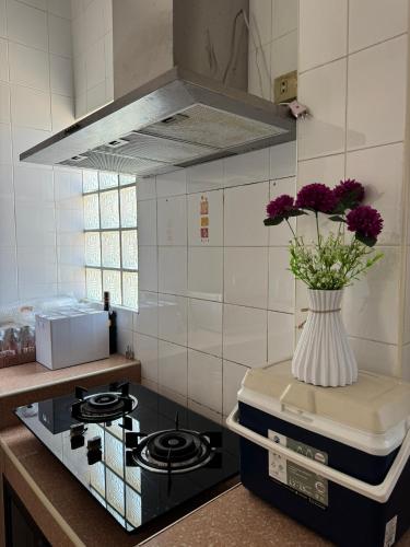 a vase of flowers on top of a stove in a kitchen at ริมน้ำบ้านแม่ อัมพวา เหมาหลัง 5 นอน พักได้ 10 คน in Samut Songkhram