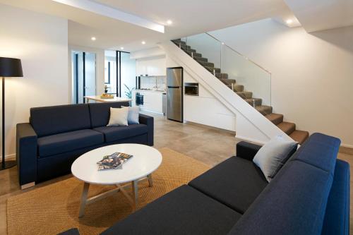 a living room with two blue couches and a table at Veriu Camperdown in Sydney
