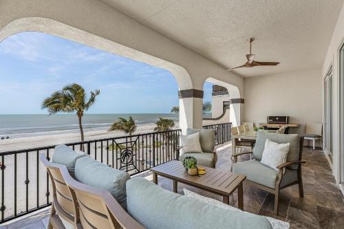 a living room with a balcony with a view of the beach at Curious Tides Gulf-Front 10BR Estate- Private Pools, Spas, Views townhouse in Fort Myers Beach