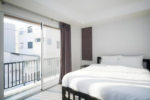 a bedroom with a white bed and a balcony at Mitr Inn The Grand Palace Bangkok - Mrt Samyot Station Pro in Bangkok