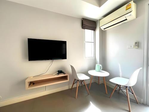 a living room with a tv and two chairs and a table at Mitr Inn The Grand Palace Bangkok - Mrt Samyot Station Pro in Bangkok