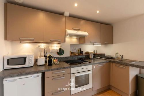 une cuisine avec des appareils électroménagers en acier inoxydable et des armoires brunes dans l'établissement The Duplex Varin Beautiful Apartment & Garden Honfleur 4 People, à Honfleur