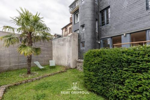 un palmier dans une cour à côté d'une maison dans l'établissement The Duplex Varin Beautiful Apartment & Garden Honfleur 4 People, à Honfleur