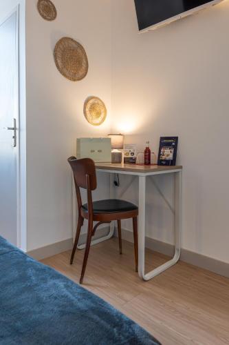 a desk in a room with a chair and a laptop at Hôtel Océan Dinan in Dinan