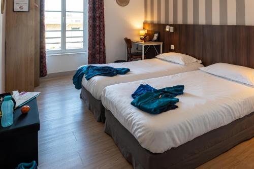 two beds in a hotel room with blue robes on them at Hôtel Océan Dinan in Dinan