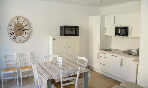 une cuisine avec une table et une horloge au mur dans l'établissement La Maison Bleue, à Cabourg