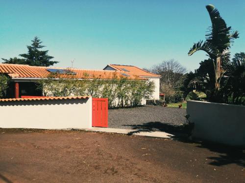 a house with a white fence and a red door at Quinta das Almas in São Roque do Pico