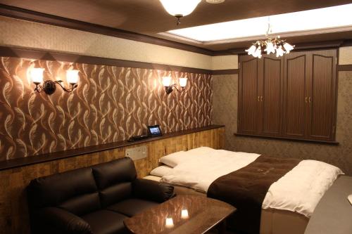 a bedroom with a bed and a couch and a table at ホテル アンジュエトワール 堺 - Adult Only in Sakai