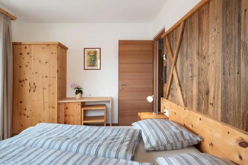 a bedroom with a bed and a wooden wall at Haus Pferscher in Barbiano