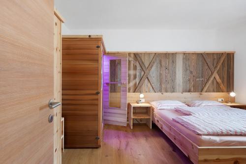 a bedroom with a bed and a wooden wall at Haus Pferscher in Barbiano