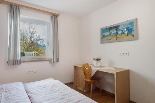 a bedroom with a bed and a desk and a window at Haus Pferscher in Barbiano