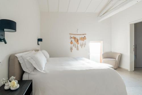 a white bedroom with a white bed and a chair at One Belvedere Tuscany in Poggibonsi
