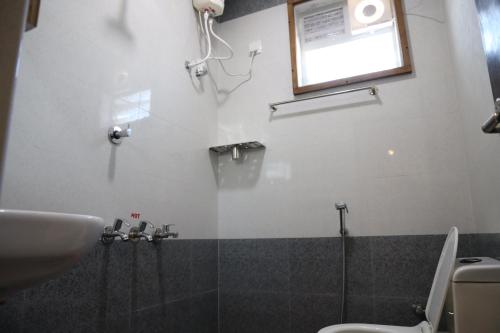 a bathroom with a sink and a toilet and a window at Kalyan Residency By Azalea in Madurai
