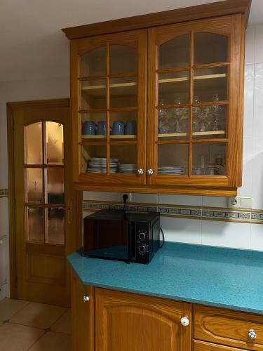 a kitchen with wooden cabinets and a microwave at Casa Rural Roa in Casinos