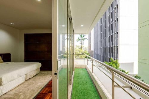 a bedroom with a bed and a balcony with green grass at Ma Peng Seng Apartment in Bangkok