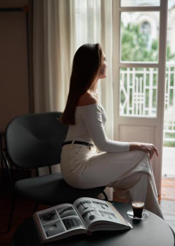 a woman sitting on a chair looking out a window at Heart Hotel in Limassol