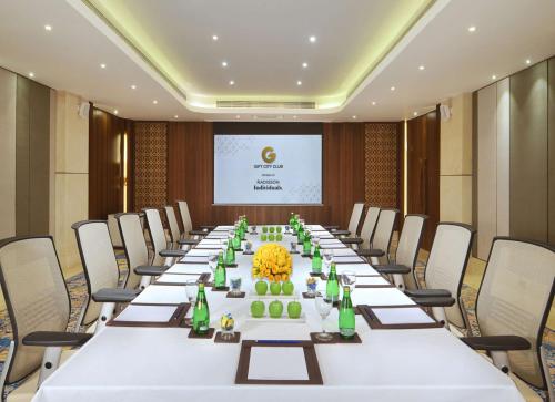 a long table in a room with chairs and a screen at Gift City Club, a member of Radisson Individuals in Gandhinagar