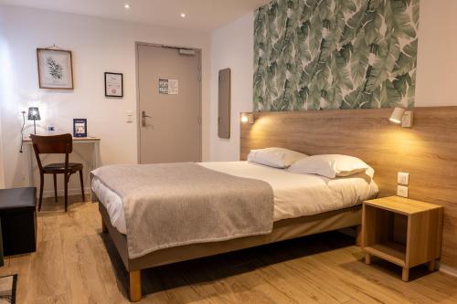 a bedroom with a bed and a table with a chair at Hôtel Océan Dinan in Dinan