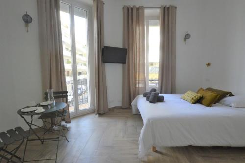 une chambre d'hôtel avec un lit, une table et des fenêtres dans l'établissement Studio entre plage et centre Cannes, à Cannes