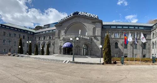 a large building with flags in front of it at Moselle Armenia Wellness & Medical SPA Jermuk in Jermuk