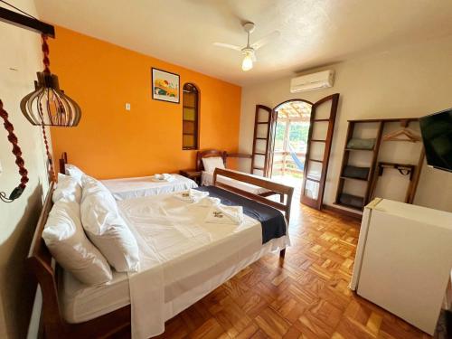 a bedroom with a bed with an orange wall at Pousada Recanto da Ladeira in Paraty