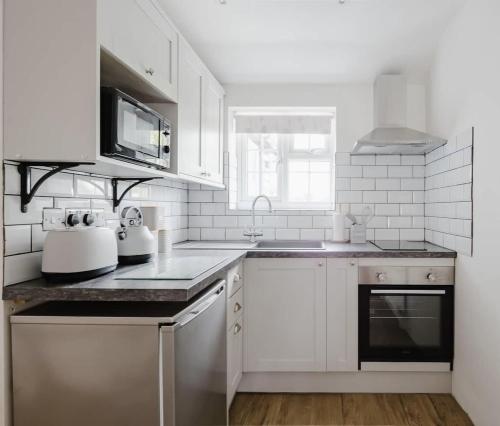 a white kitchen with a sink and a microwave at Great Sampford B&B Sorrells farm in Hempstead