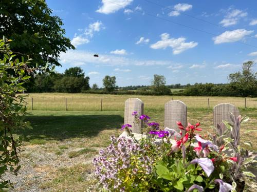 a group of tombstones in a cemetery with flowers at Great Sampford B&B Sorrells farm in Hempstead