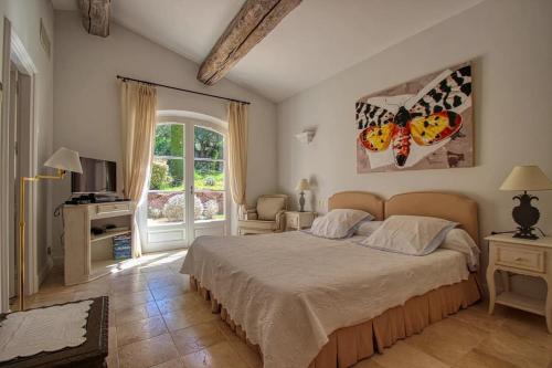 une chambre avec un grand lit et une fenêtre dans l'établissement Le Mas Ramatuelle, à Ramatuelle