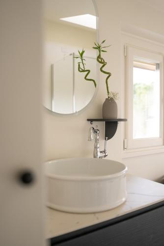 a white bathroom with a sink and a mirror at One Belvedere Tuscany in Poggibonsi