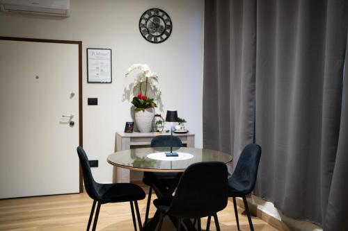 a table and chairs in a room with a clock on the wall at casa con veranda e idromassaggio in Barletta