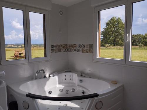 La salle de bains est pourvue d'une baignoire blanche et de 2 fenêtres. dans l'établissement So Romantic - Le Moulin de Camargois, à Avessac