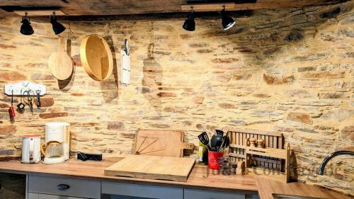 - une cuisine avec un comptoir et un mur en pierre dans l'établissement So Romantic - Le Moulin de Camargois, à Avessac
