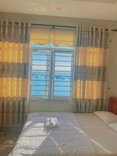 a bedroom with a bed and a window with towels on it at Nhà nghỉ Majestic Cô Tô in Quang Ninh