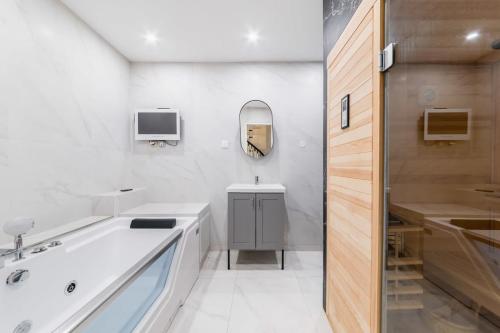 une salle de bain avec une baignoire, un lavabo et un miroir dans l'établissement Spa prive a domicile - Sauna elegance a Paris 17, à Paris
