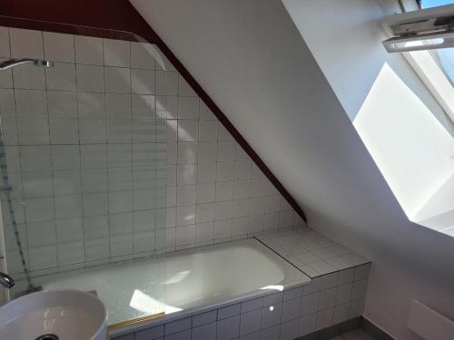 La salle de bains mansardée est pourvue d'une baignoire. dans l'établissement Family Home Between Land Sea Maison Familial Entre Terre et Mer Avec piscine, à Plédran