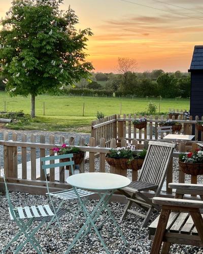 a patio with tables and chairs and a fence at Great Sampford B&B Sorrells farm in Hempstead
